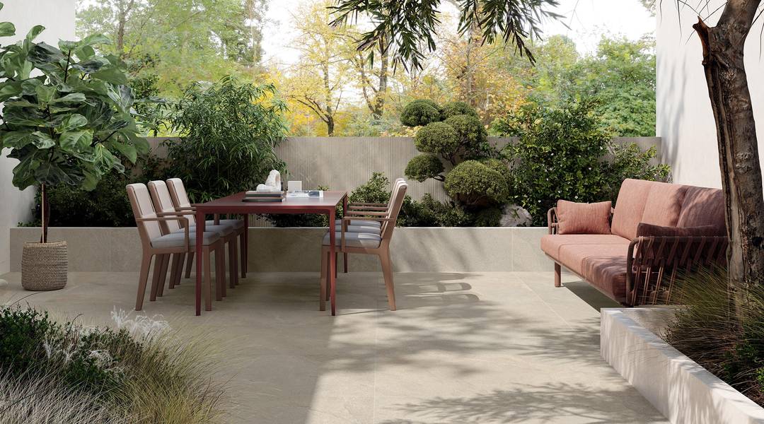 Außenterrasse mit Steinoptik‑Boden und Esstisch.