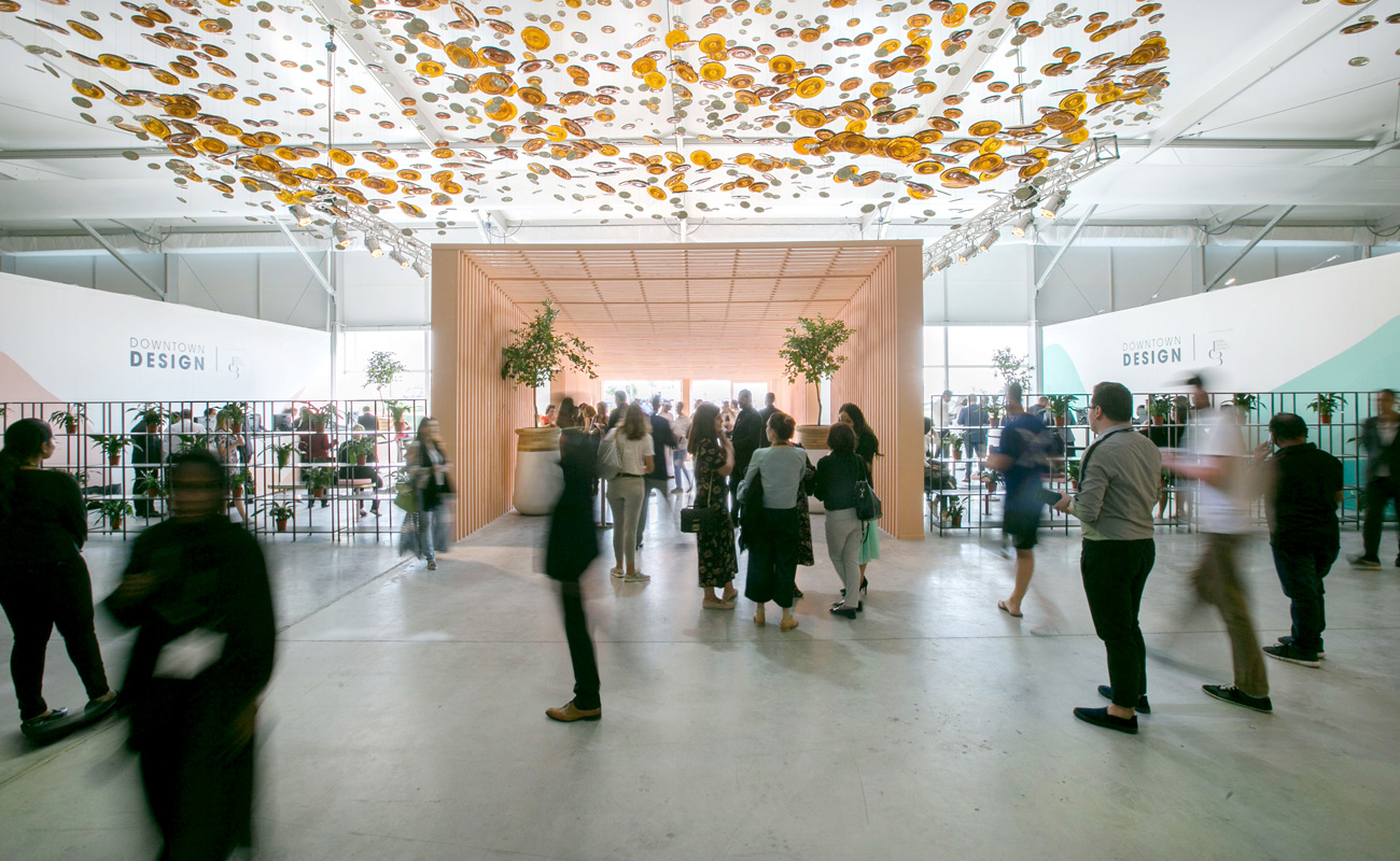 Design exhibition space with a suspended art installation and people walking during an event.