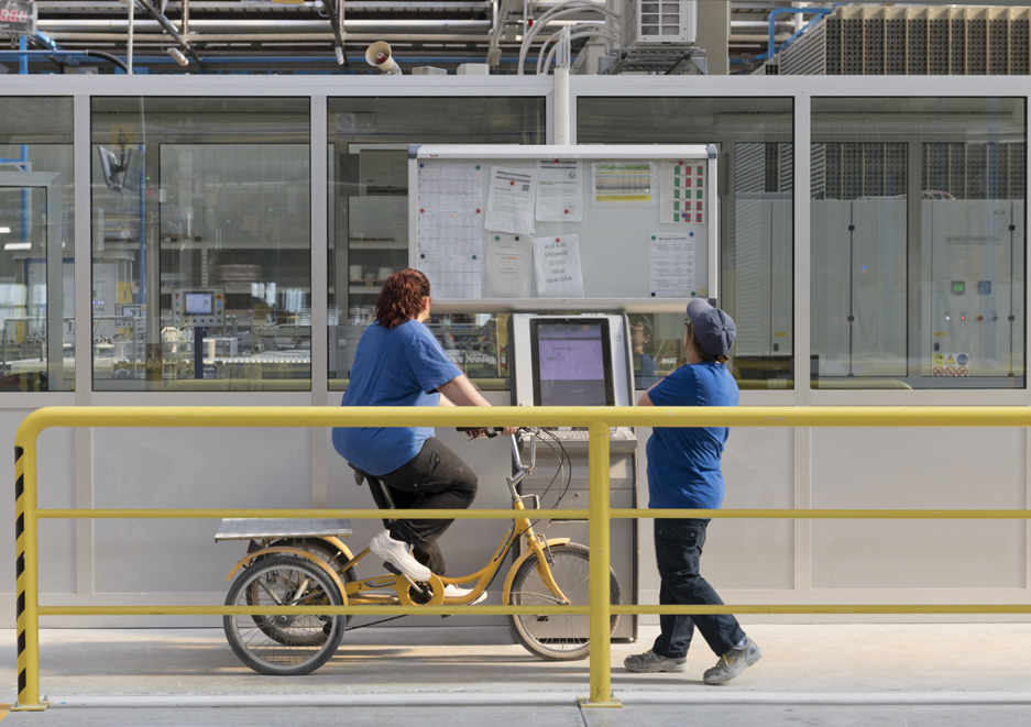Two operators at the terminal in the production department, one on a bicycle, symbolising sustainable internal mobility and an active industrial environment.