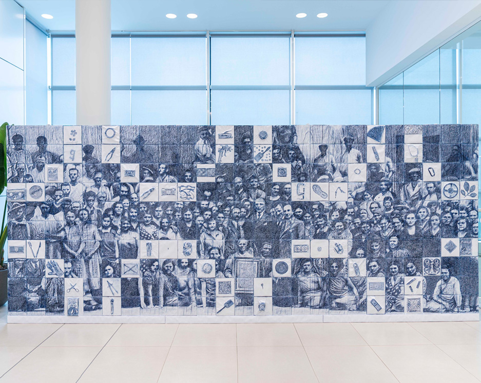 Wall decorated with a tile mosaic depicting faces and symbols related to ceramics and history.