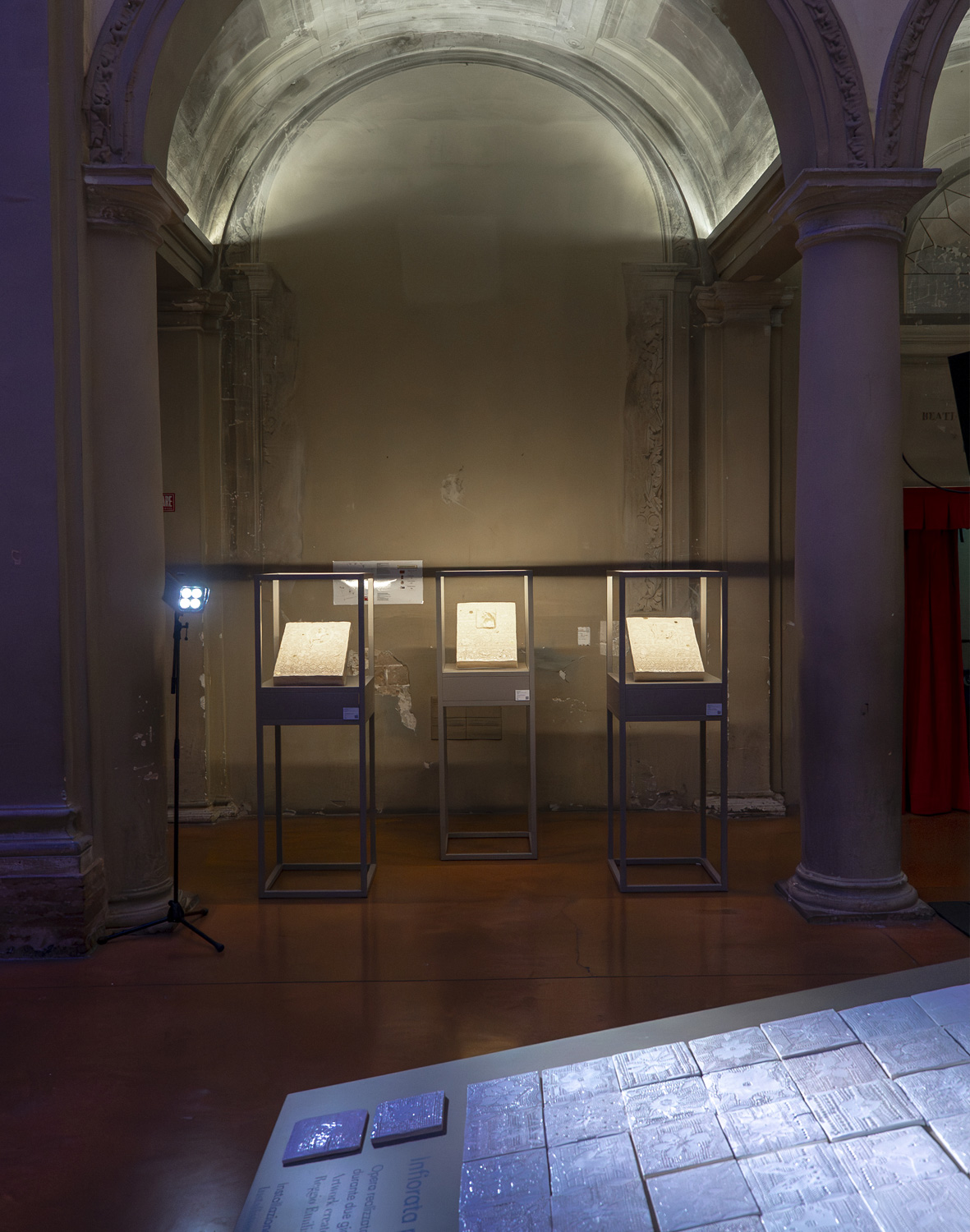 Opere in ceramica esposte in teche illuminate sotto un arco monumentale.