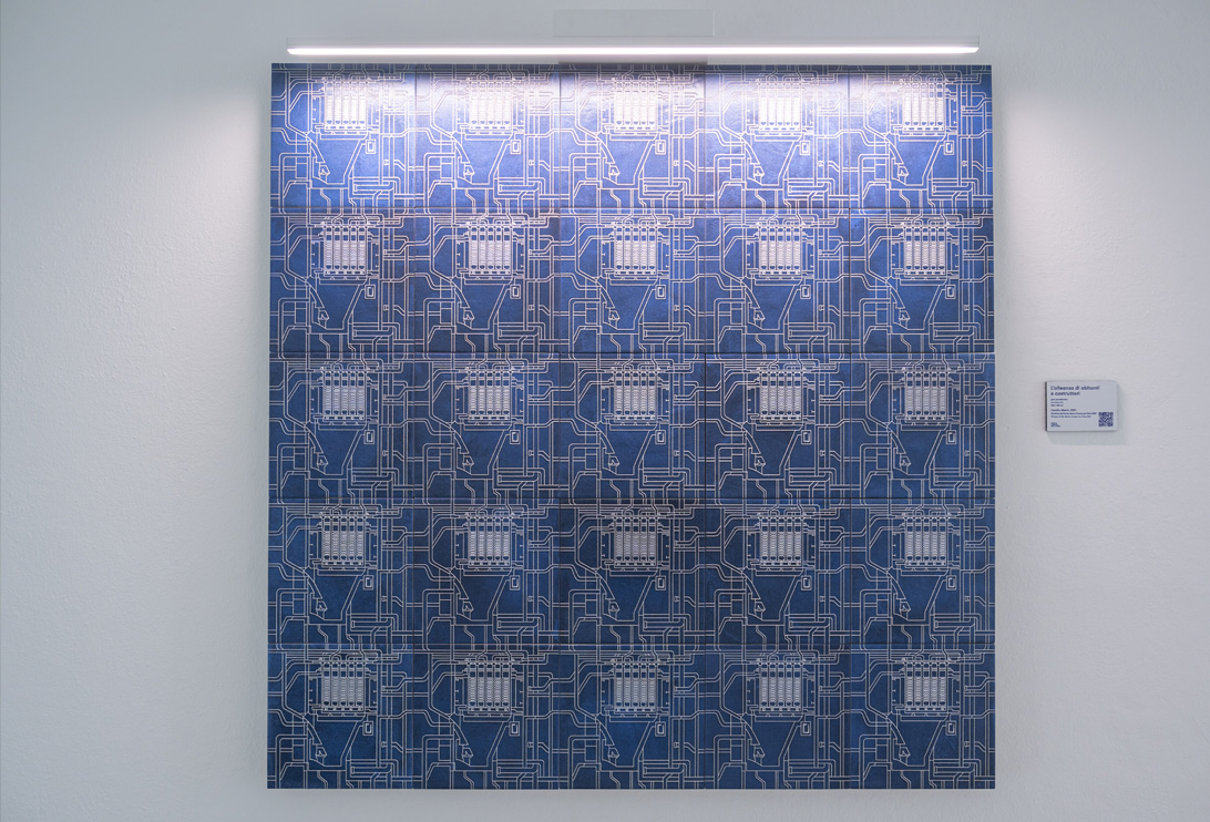 Blue ceramic panel with technical graphics of industrial plants, illuminated by LED light and mounted on a white wall.