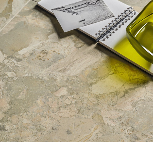 Detail of beige marble-effect stoneware surface, notebook with photograph and green glass bowl.
