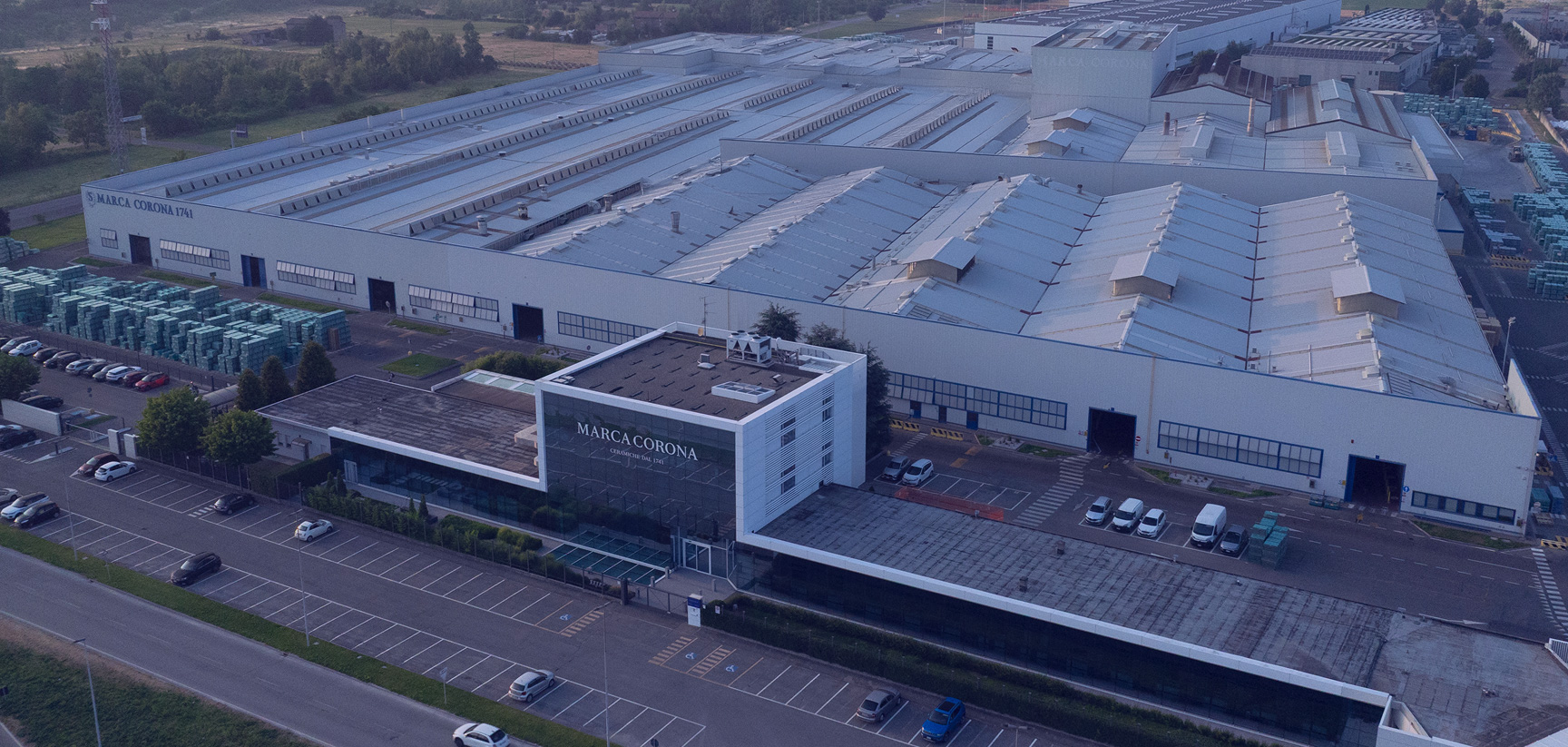 Aerial view of the Marca Corona factory in Sassuolo, home to one of Italy’s leading porcelain tile manufacturers, with warehouse, offices and car parks surrounded by the green countryside of Emilia.