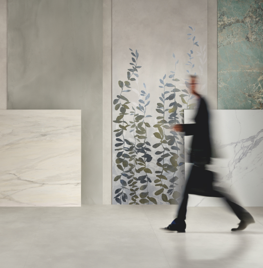 Exhibition space with marble-effect ceramic slabs and large decorated slabs, moving figure.