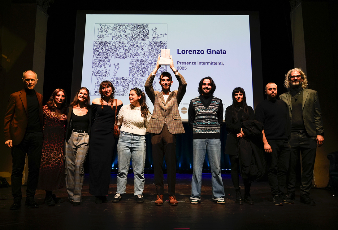 Award ceremony: Lorenzo Gnata raises the trophy while the group of artists stands beside him.