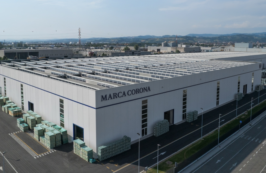 Aerial view of the Marca Corona factory with solar panels on the roof and pallets of tiles outside.