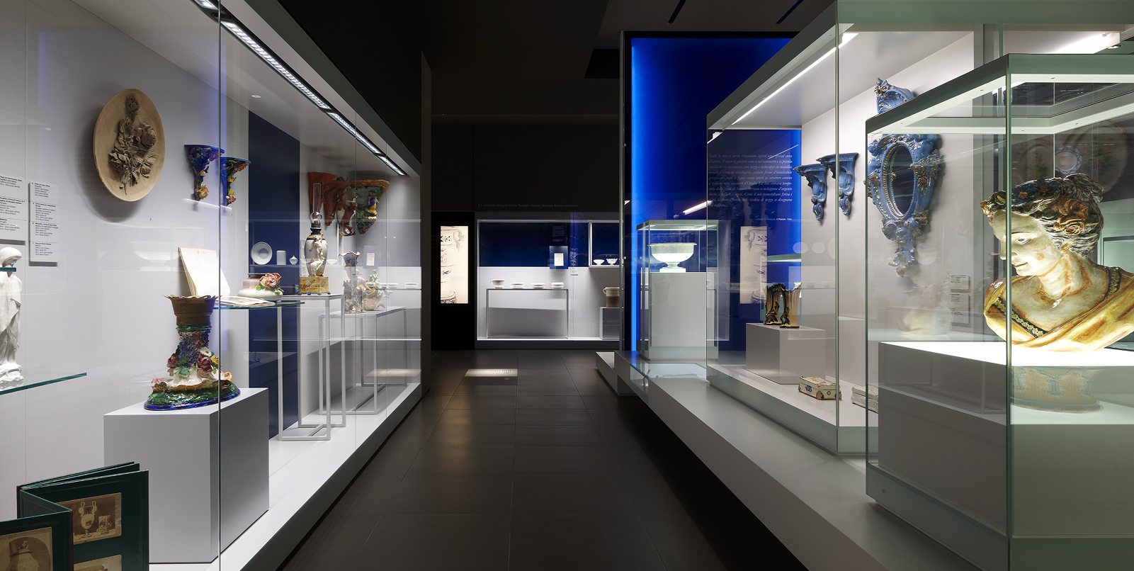 Exhibition gallery with ceramic works, Renaissance busts and artistic artefacts displayed in glass cases.