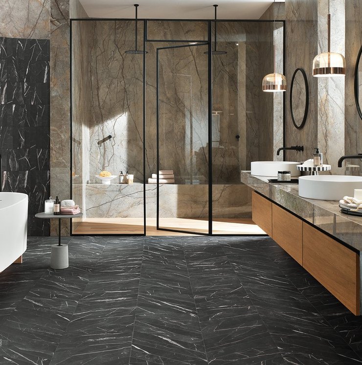 Elegantes Badezimmer mit Wänden in brauner Marmoroptik und schwarzem, gemasertem Boden, Holzmöbeln und freistehender weißer Badewanne.