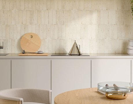 Cucina con rivestimento beige a brick , piano cucina taupe con rubinetto acciaio e tagliere legno chiaro, tavolo di legno e sedia.