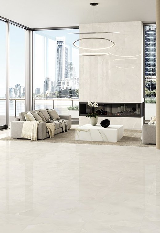 Modernes Wohnzimmer mit Böden und Wänden aus Feinsteinzeug in weißer Marmoroptik, großen Fenstern und Sofas in Beigetönen.