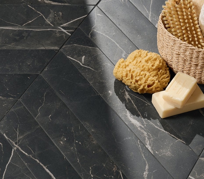 Bodenbelag aus Feinsteinzeug in schwarzer Marmoroptik mit weißen Adern und matter Oberfläche, Badaccessoires wie Schwamm und Naturseife.