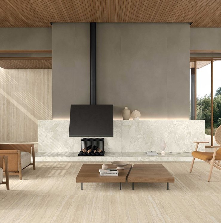 Wohnbereich mit Boden und Verkleidungen in beiger Travertinoptik, Möbeln aus Holz und Leder und Details im zeitgenössischen Stil.