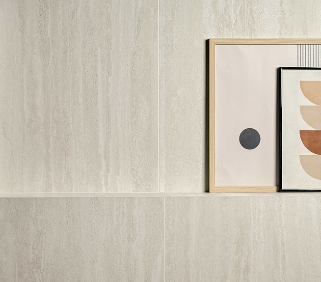 Wandverkleidung mit hellen Travertinoptik-Platten, verziert mit geometrischen Drucken in Naturholzrahmen.