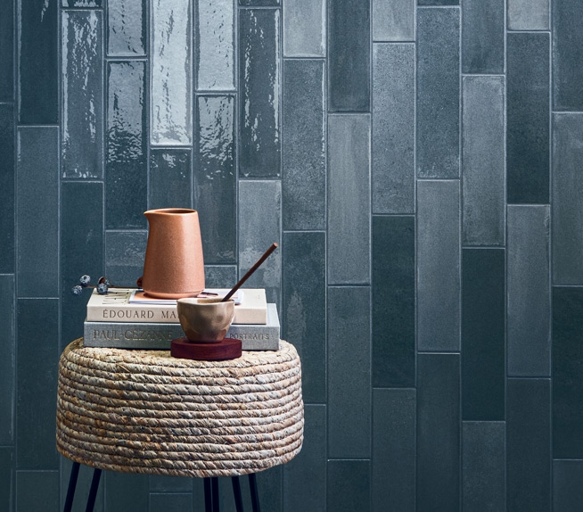 Parete con piastrelle blu lucide e tavolino con oggetti decorativi.