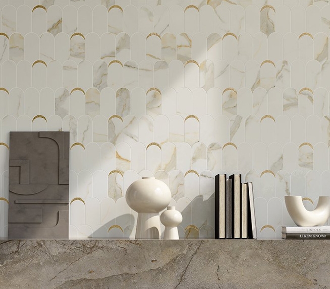 Wand mit Fliesen in Marmoroptik und goldenen Einsätzen, Regal aus Feinsteinzeug in Steinoptik mit modernen Dekorationsgegenständen.