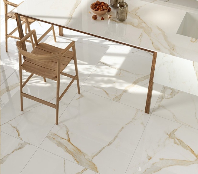 Helle Küche mit Boden und Arbeitsplatte in weißer Marmoroptik mit Goldmaserung, kombiniert mit Hockern aus Naturholz.