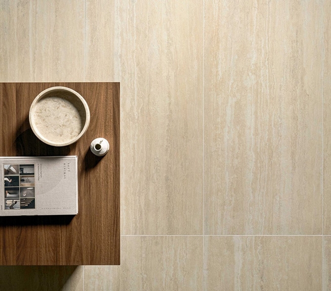 Bodenbelag in beigefarbenem Travertinoptik mit matter Oberfläche, Holzmöbel und Keramikaccessoires in neutralen Farbtönen.