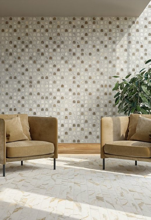 Heller Loungebereich mit Boden und Wand in beige-goldener Marmoroptik, ockerfarbenen Sesseln und Möbeln aus Naturholz.