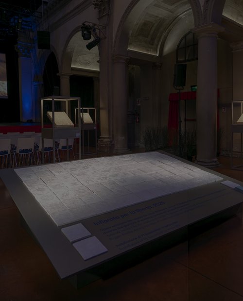 Instalación de baldosas cerámicas expuesta en una sala histórica con arcos y columnas.