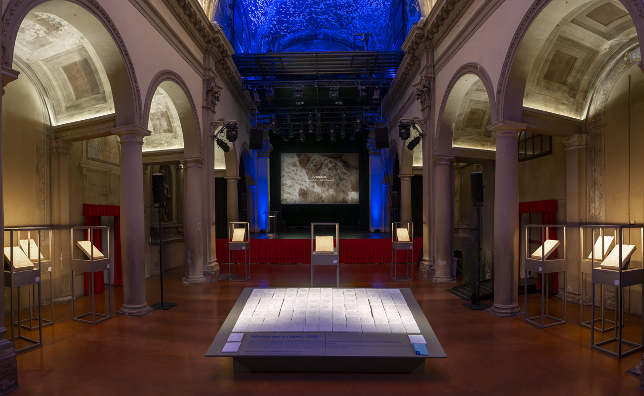 Vista panoramica della mostra con installazioni in ceramica e palco illuminato.