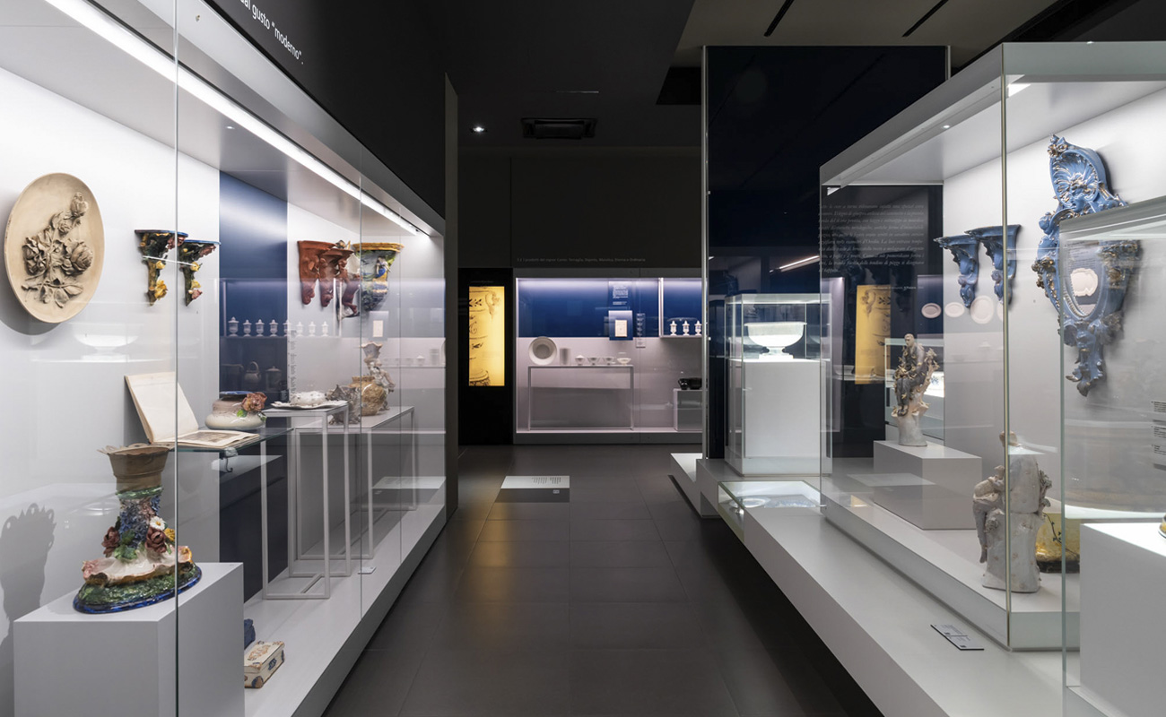 Vetrine espositive della Galleria Marca Corona con opere in ceramica, rilievi floreali e sculture settecentesche in un allestimento moderno.