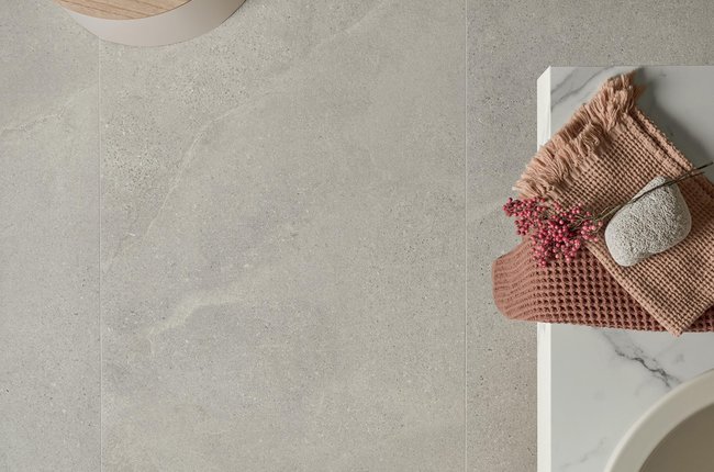Bathroom floor in grey stone‑effect porcelain with sink and accessories.