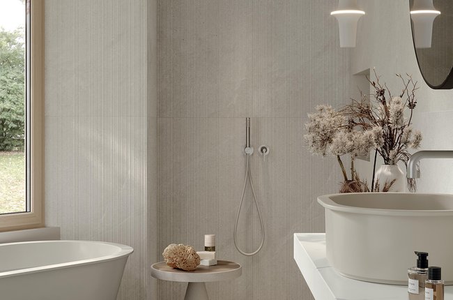 Baño elegante con bañera, ducha y azulejos efecto piedra.