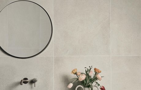 Bathroom wall with large beige stone‑effect porcelain slabs and sink.