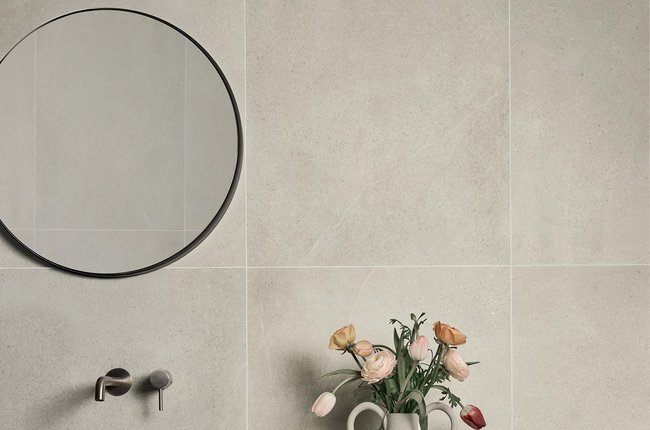Bathroom wall with large beige stone‑effect porcelain slabs and sink.