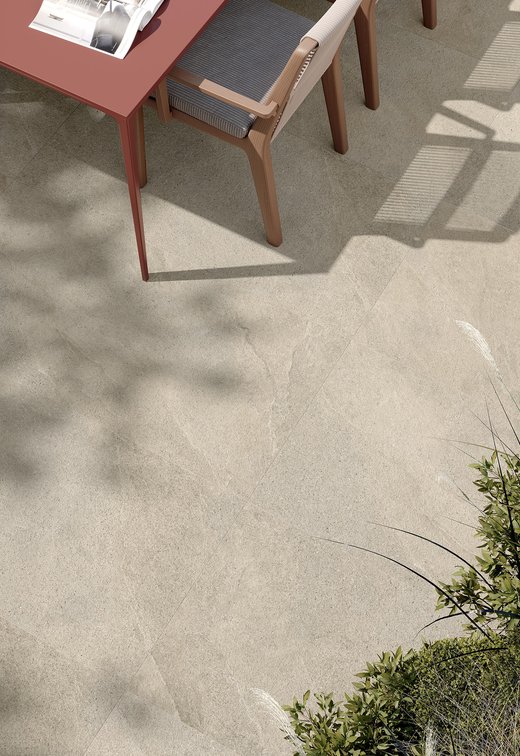 Detail of outdoor stone‑effect porcelain flooring with plant shadows.
