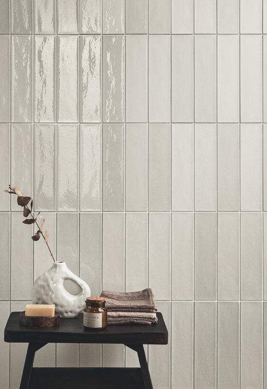Bathroom detail with light glazed tiles and decorative table.