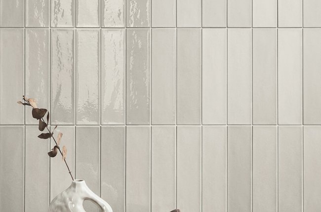 Bathroom detail with light glazed tiles and decorative table.