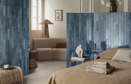 Спальня со стенами из глянцевой синей плитки.