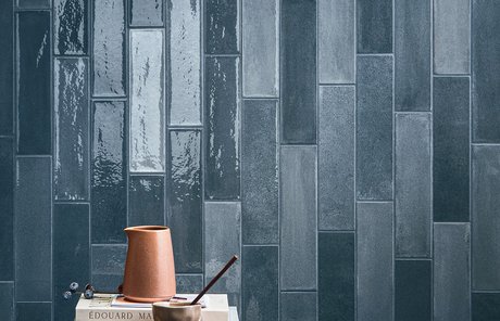 Wall with glossy blue tiles and side table with decorative objects.