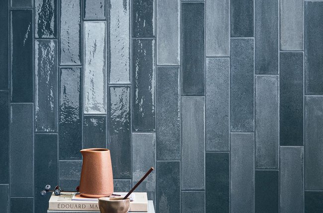 Wall with glossy blue tiles and side table with decorative objects.